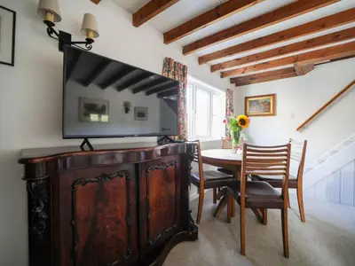 a dining room with a table and a television on top at Rose Hill Cottage in Port Isaac
