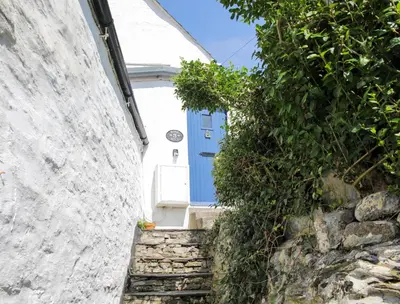 a blue door on a white house with stairs at Rose Hill Cottage in Port Isaac