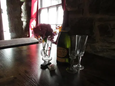 a bottle of beer and two glasses on a table at Cornwall Log Burner no cleaning fee in Camborne