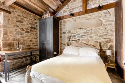 a bed in a room with a stone wall at Cornwall Log Burner no cleaning fee in Camborne