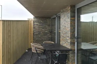 an outdoor patio with a wooden table and chairs at Groundfloor Apartment Opposite Beach with Parking in Newquay