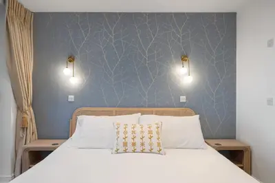 a bedroom with a bed with two lights on the wall at Modern Groundfloor Apartment with Private Parking in Newquay