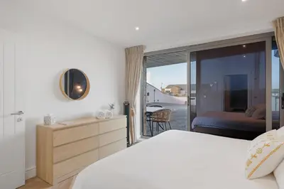 a bedroom with a bed and a view of a balcony at Modern Groundfloor Apartment with Private Parking in Newquay