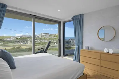 a bedroom with a bed and a large window at Modern Apartment with Balcony Sea Views & Parking in Newquay
