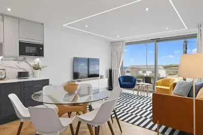 a kitchen and living room with a glass table and chairs at Modern Apartment with Balcony Sea Views & Parking in Newquay