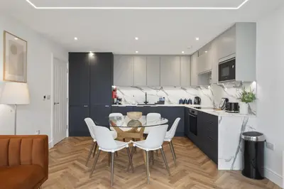 a kitchen with a glass table and white chairs at Modern Apartment with Balcony Sea Views & Parking in Newquay