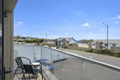 a balcony with two chairs and a view of a street at Modern Apartment with Balcony Sea Views & Parking in Newquay