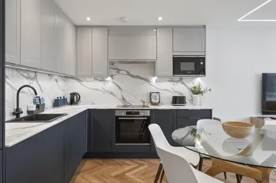 a kitchen with white cabinets and a table and chairs at Modern Apartment with Balcony Sea Views & Parking in Newquay
