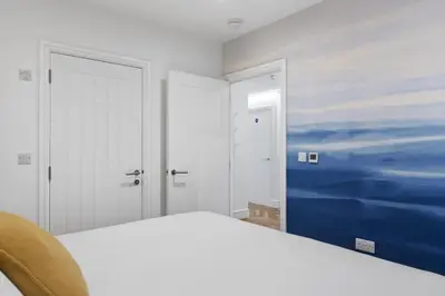a bedroom with a white bed and a painting on the wall at Modern Apartment Opposite Beach Parking & Balcony in Newquay
