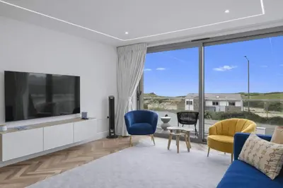 a living room with a large screen tv and chairs at Modern Apartment Opposite Beach Parking & Balcony in Newquay