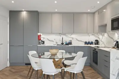 a kitchen with a glass table and white chairs at Modern Apartment Opposite Beach Parking & Balcony in Newquay