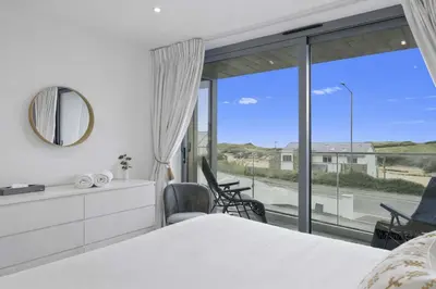 a bedroom with a bed and a large window at Modern Apartment Opposite Beach Parking & Balcony in Newquay