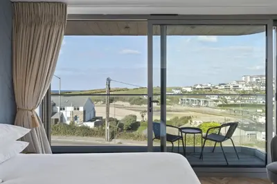 a bedroom with a bed and two chairs in front of a window at Luxurious Apartment Balcony & Sea Views Parking in Newquay
