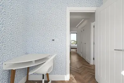 a hallway with blue and white wallpaper and a desk at Luxurious Apartment Balcony & Sea Views Parking in Newquay