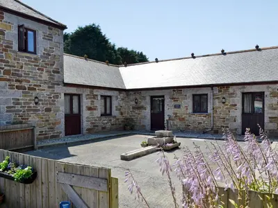 a stone building with a courtyard in front of it at Little Content Farm Cottage in Cury
