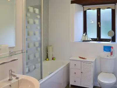 a bathroom with a toilet and a tub and a sink at Little Content Farm Cottage in Cury