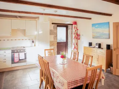 a kitchen and dining room with a table and chairs at Little Content Farm Cottage in Cury