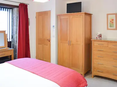 a bedroom with a bed and a cabinet and a television at Little Content Farm Cottage in Cury