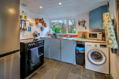 a kitchen with blue cabinets and a washer and dryer at Finest Retreats - Millook Water in Poundstock