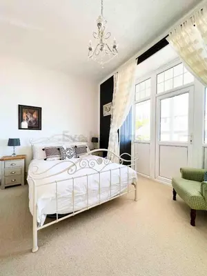 a bedroom with a white bed and a chandelier at Modern classic seaside apartment with parking and balcony in St Ives