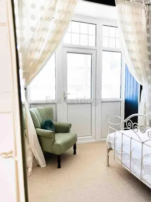 a bedroom with a chair and a bed and windows at Modern classic seaside apartment with parking and balcony in St Ives