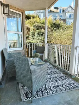 a porch with two chairs and a table and a window at Modern classic seaside apartment with parking and balcony in St Ives