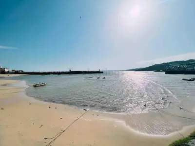 a beach with some boats in the water at Modern classic seaside apartment with parking and balcony in St Ives