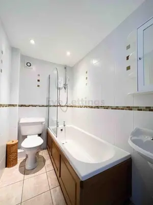 a bathroom with a tub and a toilet and a sink at Modern classic seaside apartment with parking and balcony in St Ives