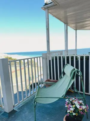 a green chair sitting on a porch overlooking the beach at Modern classic seaside apartment with parking and balcony in St Ives