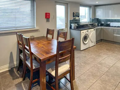 a kitchen with a wooden table and a washing machine at Number 8 in Camborne