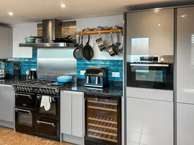 a kitchen with stainless steel appliances and blue tiles at Number 8 in Camborne