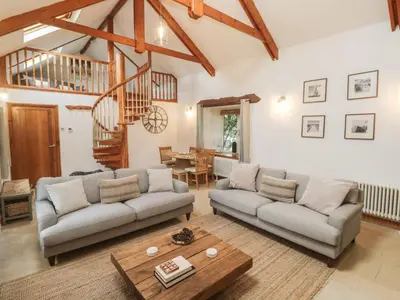 a living room with two couches and a table at Riverside Barn in Truro