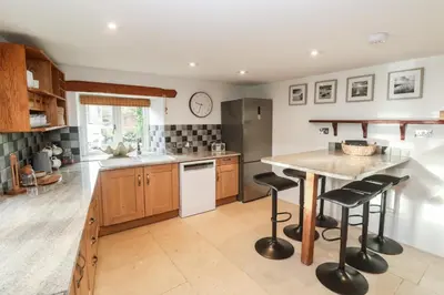 a kitchen with wooden cabinets and a island with bar stools at Riverside Barn in Truro