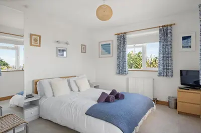 a bedroom with a large bed with a blue blanket at Spacious Home Overlooking Porthmeor Beach Parking in St Ives