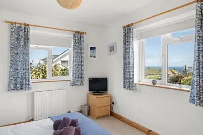 a bedroom with two windows and a television at Spacious Home Overlooking Porthmeor Beach Parking in St Ives