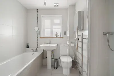 a white bathroom with a sink and a toilet at Spacious Home Overlooking Porthmeor Beach Parking in St Ives