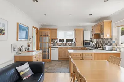a kitchen with wooden cabinets and a wooden table at Spacious Home Overlooking Porthmeor Beach Parking in St Ives