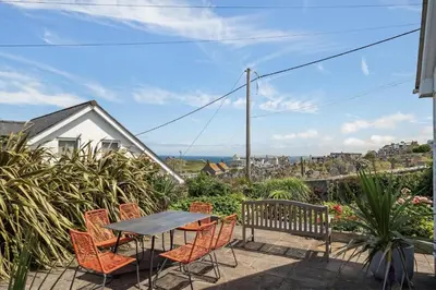 a patio with a table and chairs on a balcony at Spacious Home Overlooking Porthmeor Beach Parking in St Ives