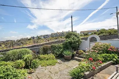 a garden with plants and flowers on a wall at Spacious Home Overlooking Porthmeor Beach Parking in St Ives