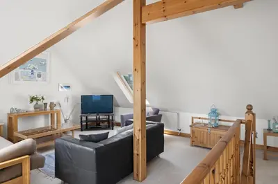a living room with a couch and a tv at Spacious Home Overlooking Porthmeor Beach Parking in St Ives