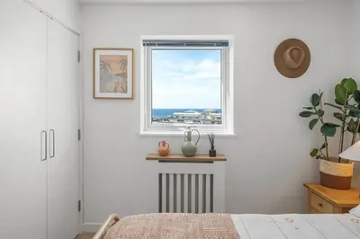 a bedroom with a window with a view of the ocean at Boho-Chic Apartment with Sea Views & Parking in Newquay