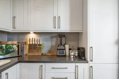 a kitchen with white cabinets and a blender on a counter at Boho-Chic Apartment with Sea Views & Parking in Newquay