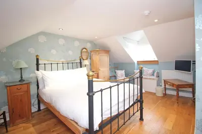 a bedroom with a bed and a desk and a window at Unique town house with games room in Padstow