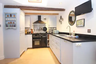 a kitchen with white cabinets and black appliances at Unique town house with games room in Padstow