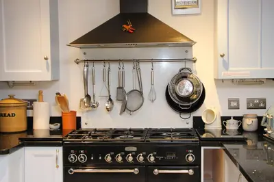 a kitchen with a stove and utensils on the wall at Unique town house with games room in Padstow