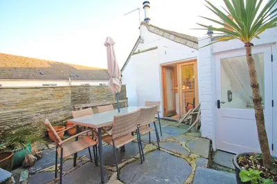 a patio with a table and chairs and a palm tree at Unique town house with games room in Padstow
