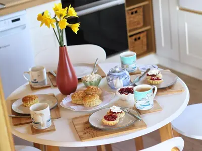 a table with plates of pastries and cups of coffee at Holiday Home für 1 Personen - 1 Kind ca- 33 m² in Ludgvan- Cornwall by Interhome in Ludgvan