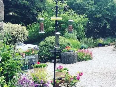 a garden with a bird feeder and some flowers at Holiday Home Idyllisches Landhaus Rosemary by Interhome in Liskeard