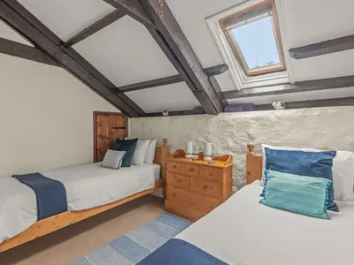 a attic bedroom with two beds and a window at Holiday Home Idyllisches-haustierfreundliches Landhaus Lavender by Interhome in Liskeard