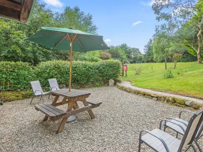 a picnic table with a green umbrella and chairs at Holiday Home Idyllisches-haustierfreundliches Landhaus Lavender by Interhome in Liskeard
